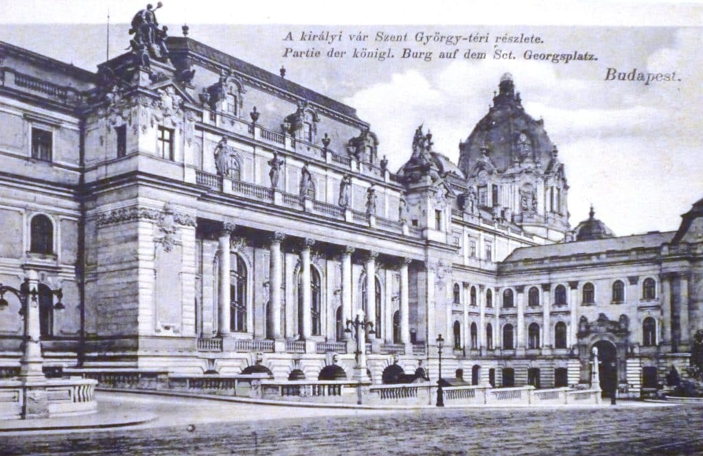 Vintage black and white postcard depicting the Royal Palace (Buda Castle) in Budapest facing St. George Square (Szent György tér). The Neo-Baroque facade features a colonnade of Corinthian columns and roofline statues, with the main dome visible in the background. Bilingual text at the top reads: "A királyi vár Szent György-téri részlete. / Partie der königl. Burg auf dem Sct. Georgsplatz."