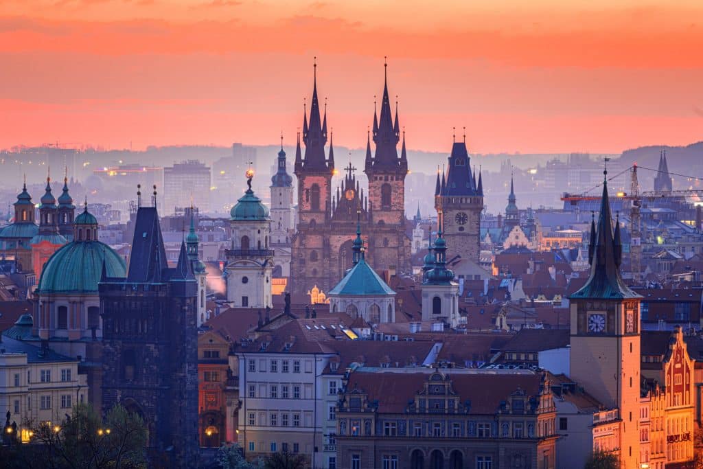Czech Republic Travel: Your Essential Guide to Exploring the Heart of Bohemia - A breathtaking sunset view of the Prague skyline, featuring the Gothic twin spires of the Church of Our Lady before Týn rising above the Old Town Bridge Tower and historic rooftops.