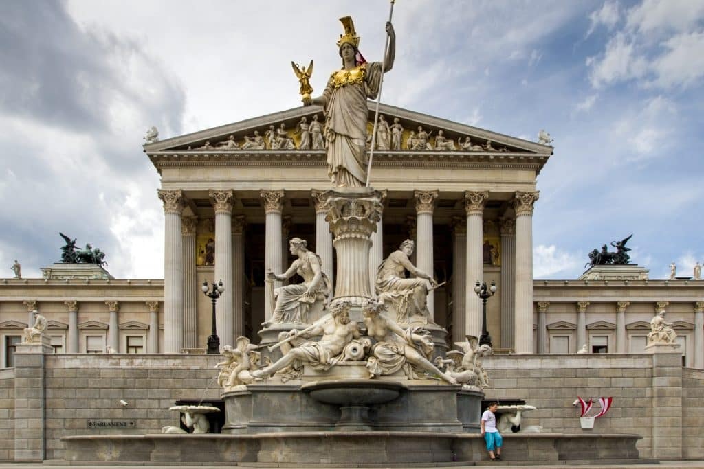 Close-up of the Pallas Athena Fountain in front of the Austrian Parliament, featuring the goddess Athena with a golden helmet and Nike in hand, surrounded by allegorical figures.
