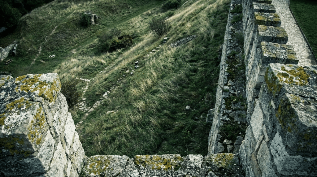 High-angle POV looking down the steep, grassy defensive slopes of Eger Castle, illustrating the difficult ascent for Ottoman soldiers during the 1552 siege.