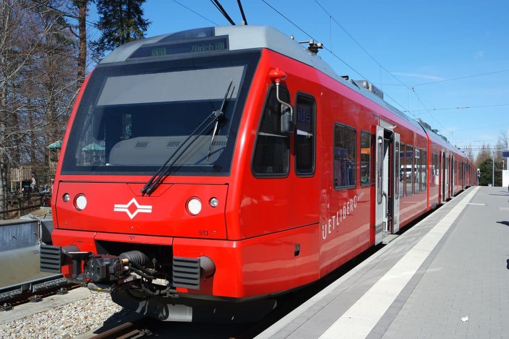 A bright red S10 train stopped at the Uetliberg platform on a sunny day.