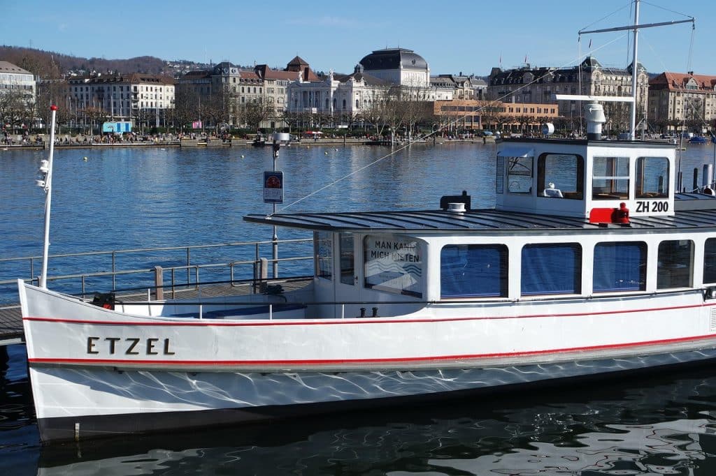 The white heritage boat 'Etzel' docked on Lake Zurich with the Opera House and city buildings in the background.