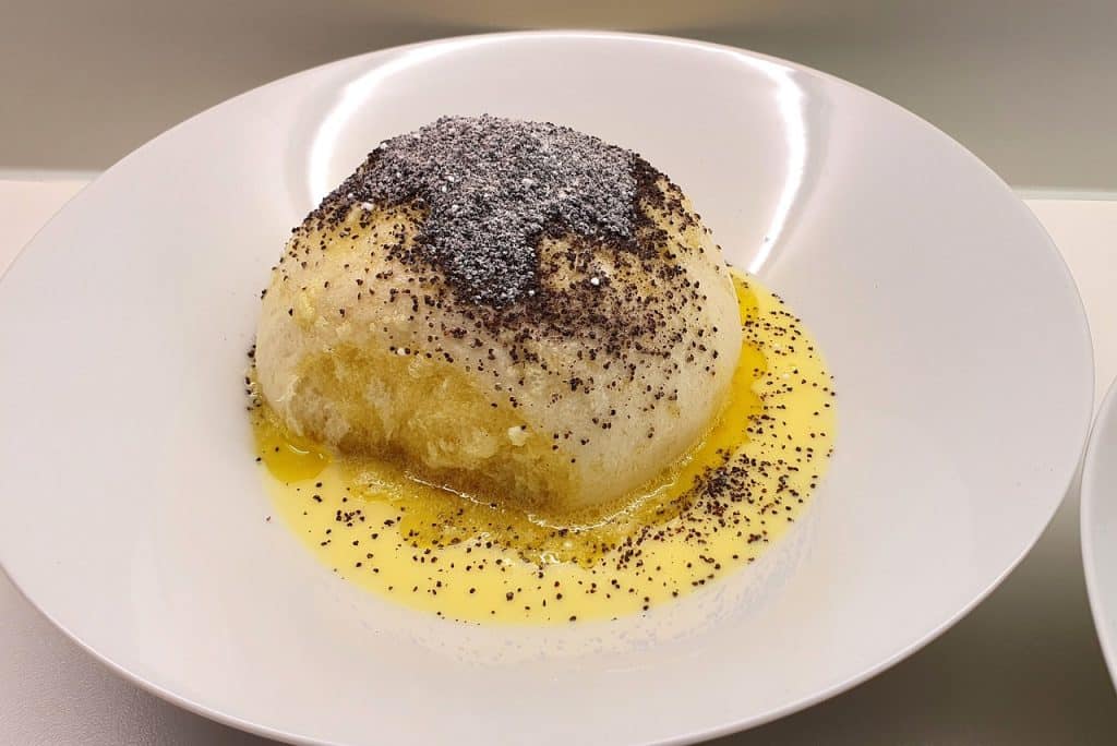 Germknödel, Austrian cuisine, dessert, yeast dumpling, vanilla sauce, poppy seeds, powdered sugar, sweet dish, Alpine food, traditional, comfort food, white bowl, close-up, food photography, pastry, Bavarian.