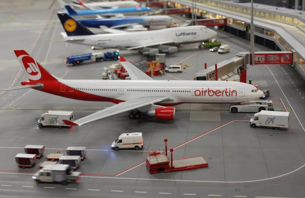 Macro photography of a miniature airport scene at Miniatur Wunderland Hamburg, showing detailed model airplanes and ground vehicles.