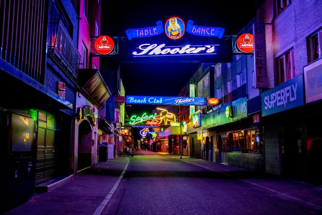 Neon signs illuminating the Reeperbahn entertainment district in Hamburg St. Pauli at night, featuring clubs and bars.