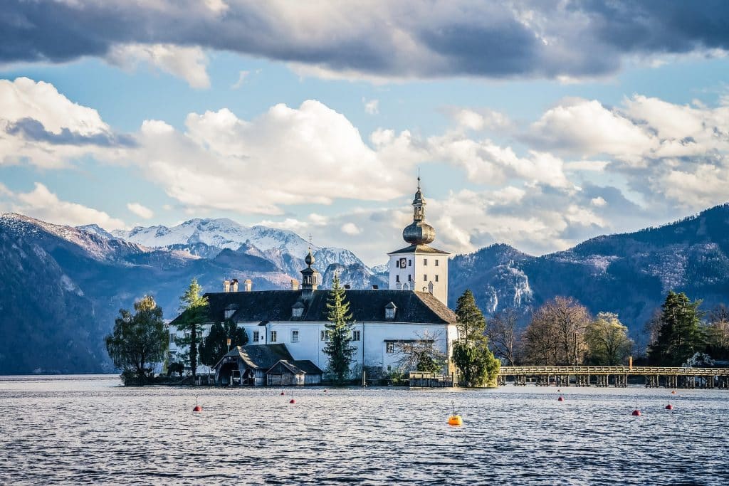 The historic Schloss Ort water castle on Traunsee near Gmunden, captured with dramatic lighting against the Alpine backdrop.