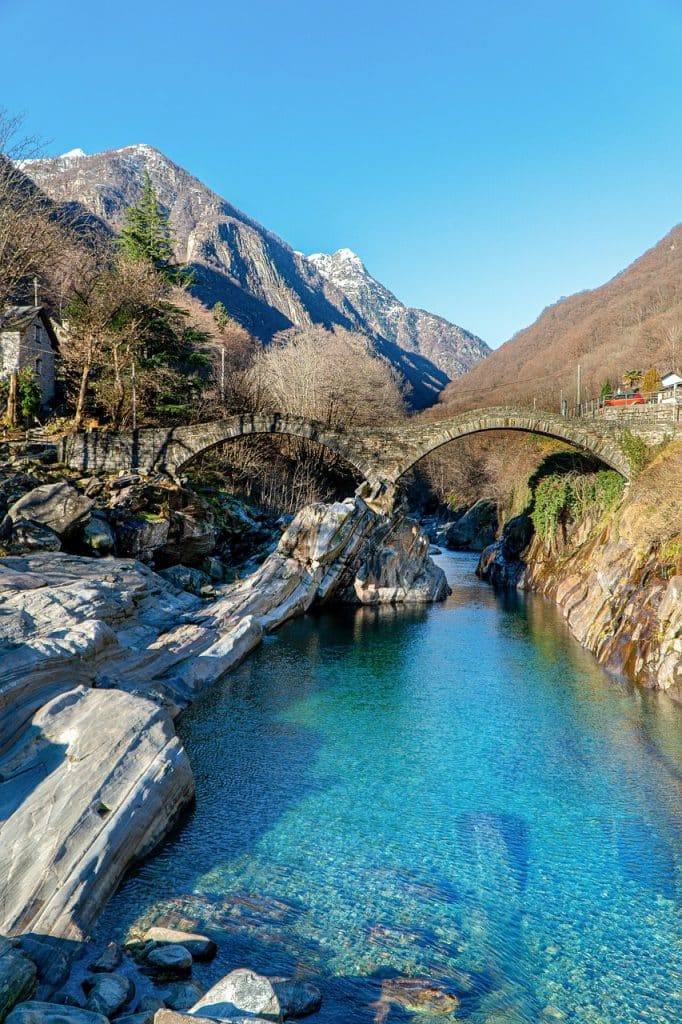 The historic double-arched stone bridge, Ponte dei Salti, spanning the turquoise waters of the Verzasca River in Lavertezzo, Switzerland.