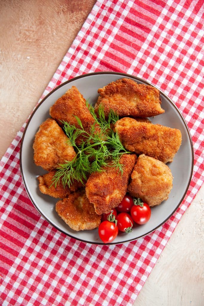 Steirisches Backhendl (Styrian fried chicken) pieces with a thin, golden crust and fresh lemon wedges.