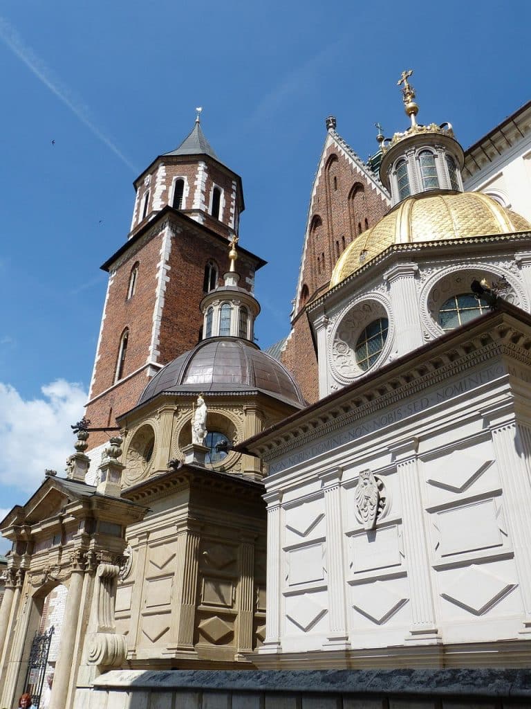 Close-up view of Wawel Cathedral showing the contrast between the ornate Renaissance golden dome of the Sigismund Chapel and the surrounding red gothic brickwork.
